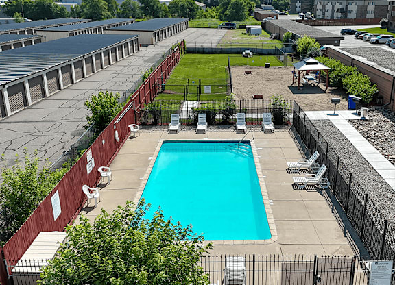 A pool surrounded by a fence and chairs.