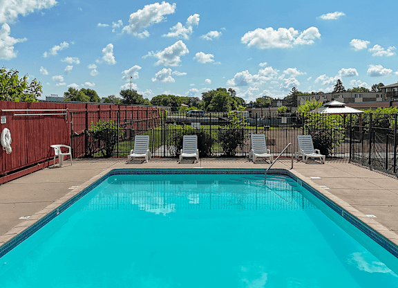 A swimming pool surrounded by a fence and chairs.