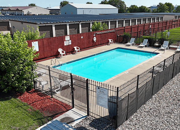 A pool surrounded by a black fence with a sign on it.