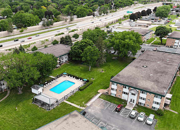 A swimming pool is surrounded by a grassy area and a building.