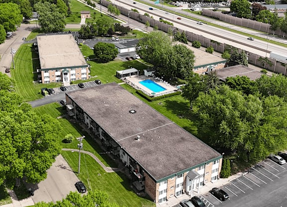 An aerial view of a building with a pool in the foreground and a highway in the background.