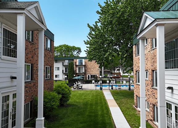 A view of a courtyard between two buildings with a white walkway.