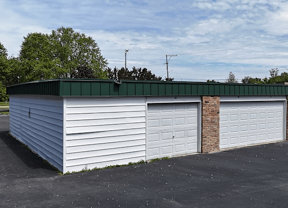 A white garage with a green roof and two doors.