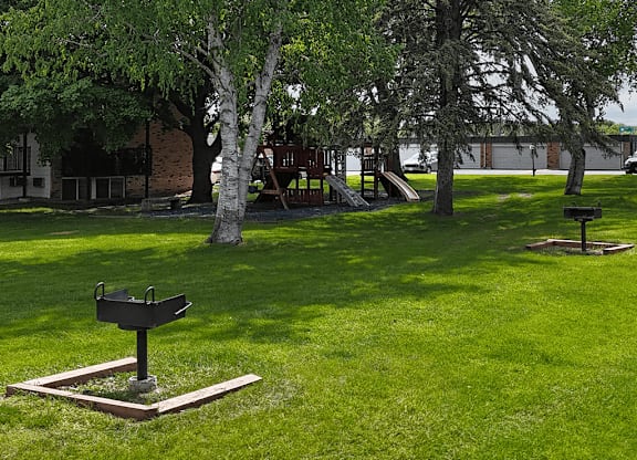 A black bird bath in a grassy area with trees in the background.