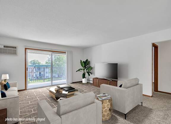 A living room with a grey couch, a coffee table, a television, and a plant.