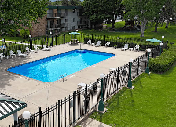 A black fence surrounds a blue swimming pool.