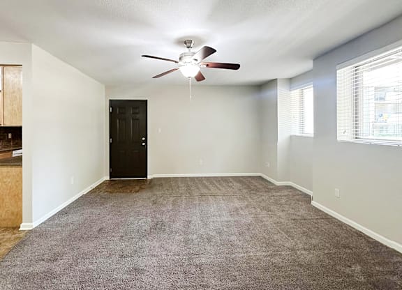 A room with a ceiling fan and carpeted floor.