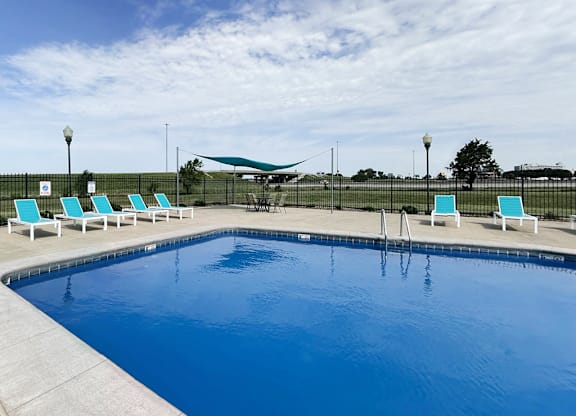 A swimming pool with blue water and white lounge chairs.