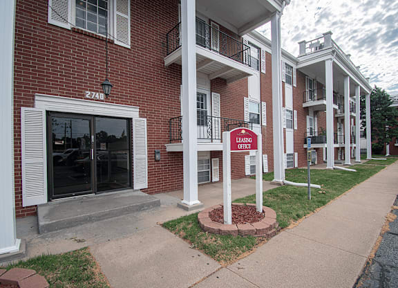 A red sign that says Leasing Office stands in front of a brick building.