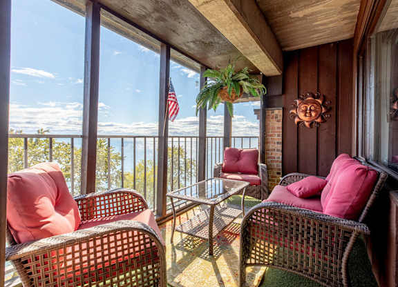 A balcony with a table and chairs overlooking the ocean.