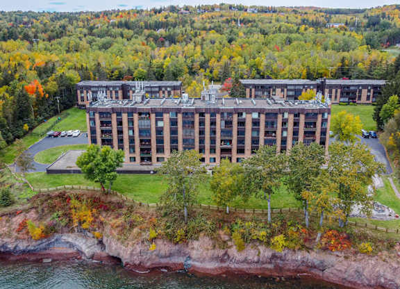 A large building sits on a cliff overlooking a body of water.