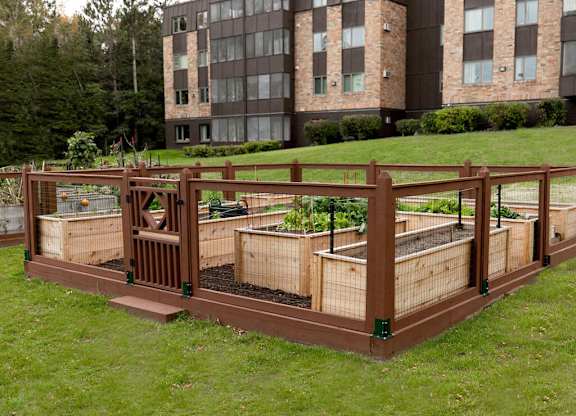 A brown raised garden bed with plants in it.