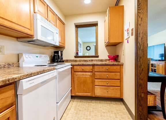 A kitchen with white appliances and wooden cabinets.