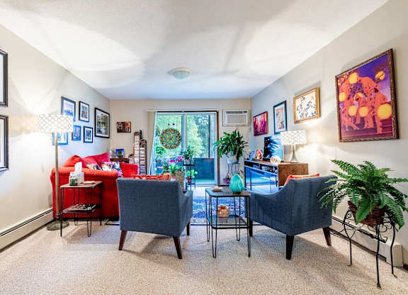 A living room with a grey couch, red couch, and a table with a vase on it.