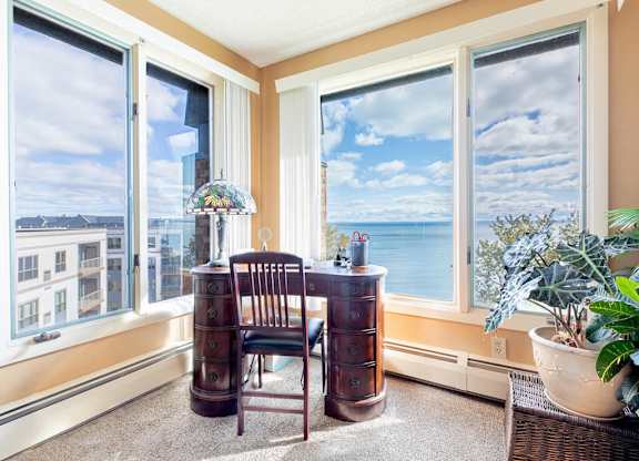 A room with a chair, a table, and a view of the city.