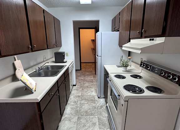 a kitchen with brown cabinets and white appliances