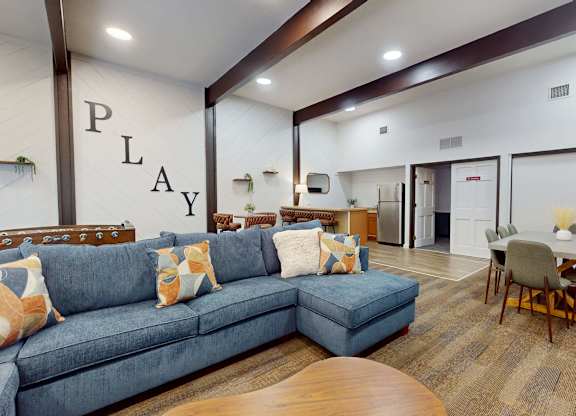 A community room with a blue couch and a wooden coffee table.