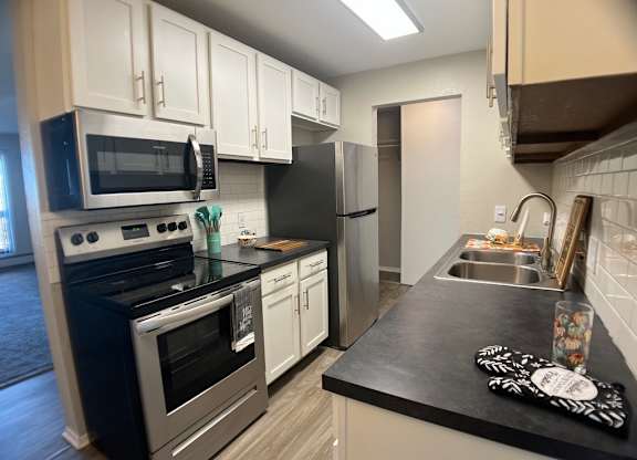 A kitchen with black countertops and stainless steel appliances.