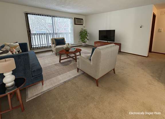 A living room with a blue couch, a brown armchair, a wooden coffee table, and a flat-screen TV.