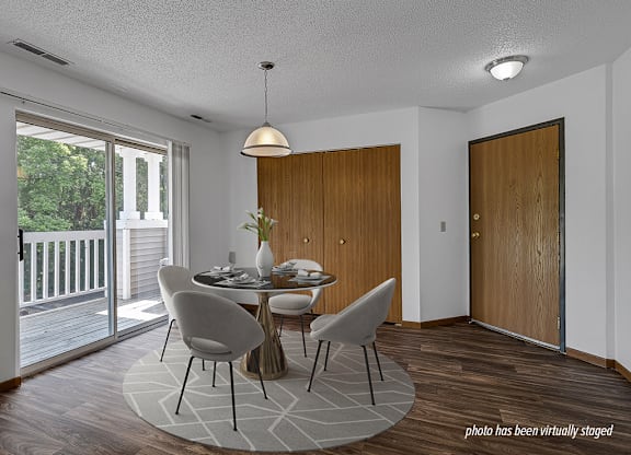 A dining room with a table set for two and a view of a deck outside.