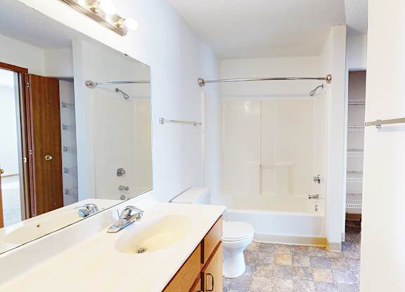 A white bathroom with a double sink and a walk in shower.