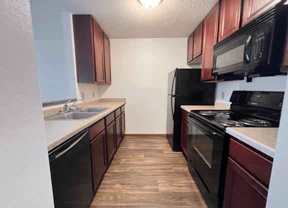 A kitchen with black appliances and brown cabinets.