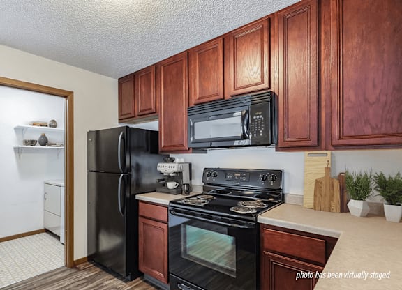 A kitchen with black appliances and wooden cabinets.