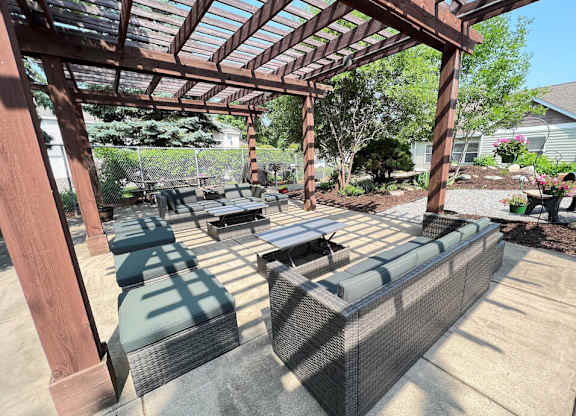a covered patio with wicker furniture and a wooden pergola