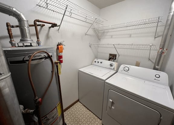 A laundry room with a washer and dryer and a hose.