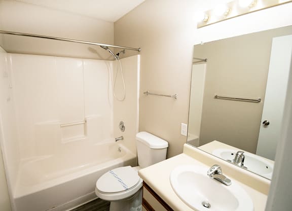 A white bathroom with a toilet, sink, and shower.