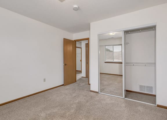 Carpeted bedroom with closet with mirror