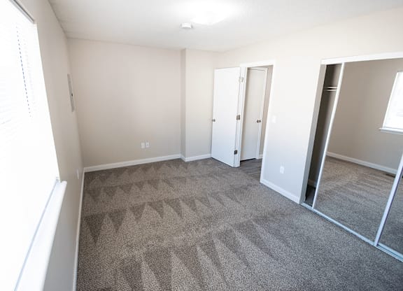 A carpeted room with a door and a window.