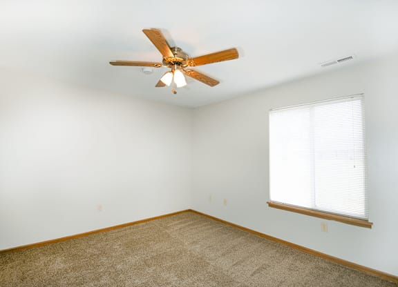 A room with a ceiling fan and a window with blinds.