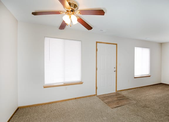 A room with a ceiling fan and carpeted floor.