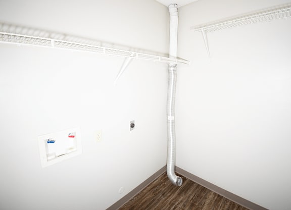 A white wall with washer and dryer connections