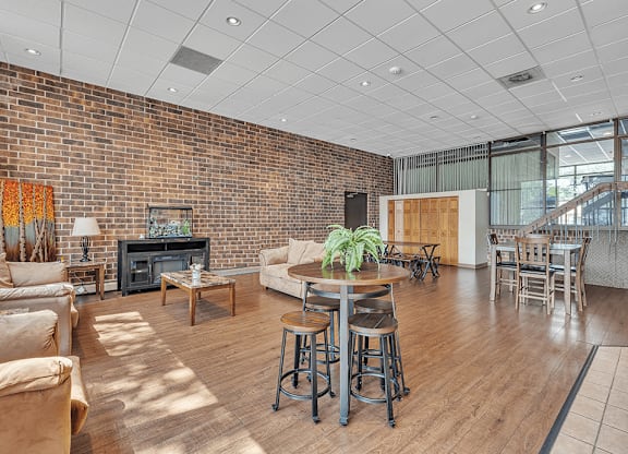a living room with a couch and a table in front of a brick wall