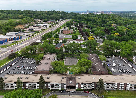A parking lot is surrounded by trees and buildings.