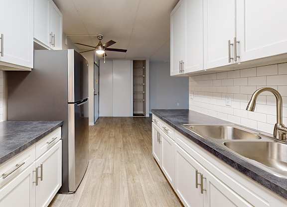 A kitchen with white cabinets and a stainless steel sink.