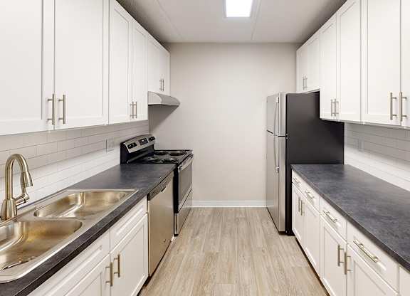 A kitchen with white cabinets and a black refrigerator.