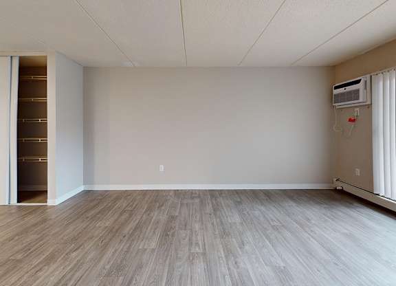 A room with a wood floor and a wall-mounted air conditioner.