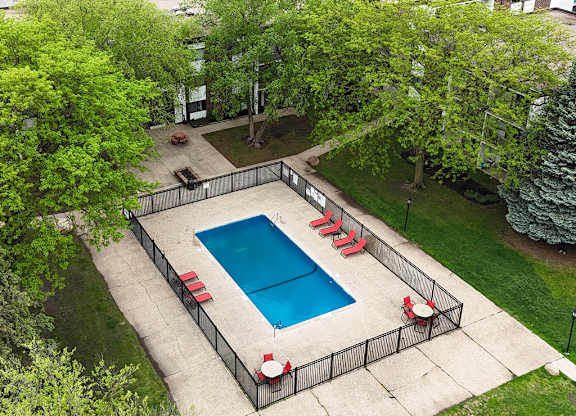 A small pool surrounded by a fence and chairs.
