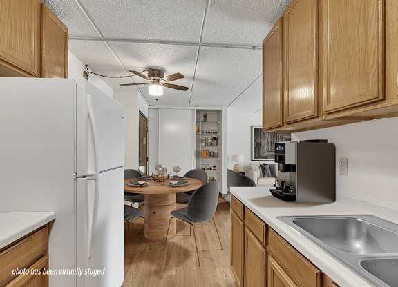 A kitchen with a white refrigerator, wooden cabinets, and a dining table with chairs.