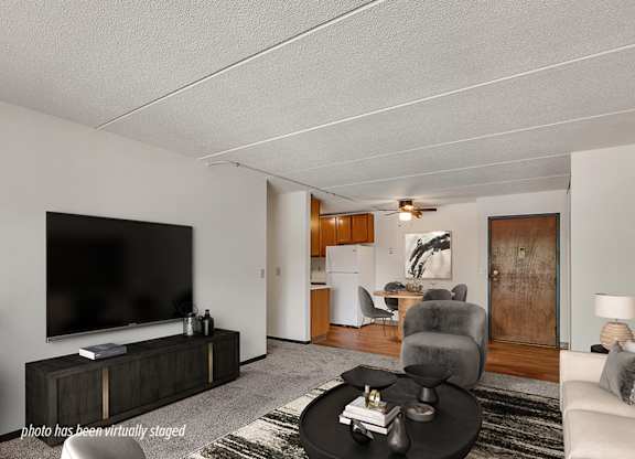 A living room with a television, a grey armchair, and a black coffee table.