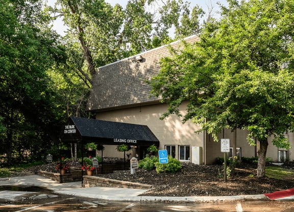 a building with a black awning and trees in front of it