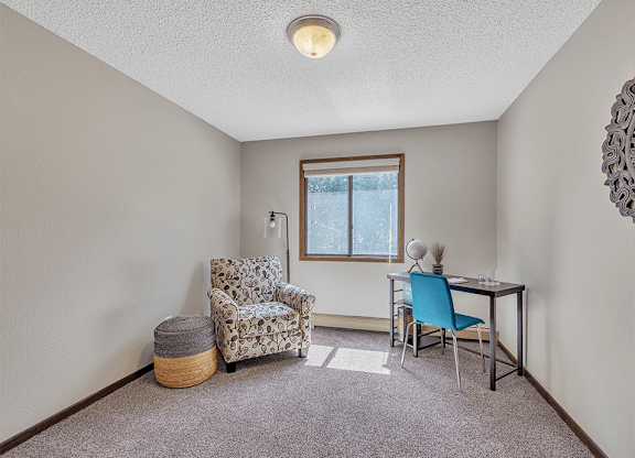 a room with a desk and chair and a window