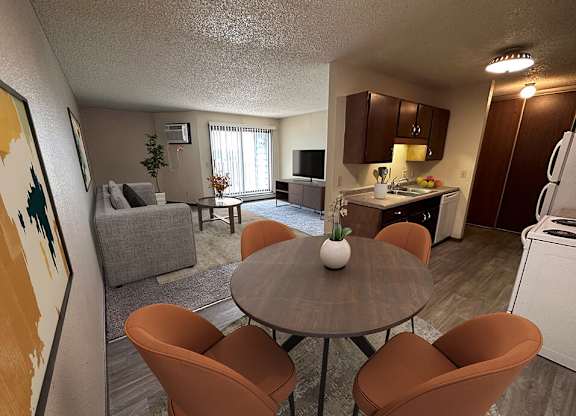 a living room with a table and chairs and a kitchen in the background