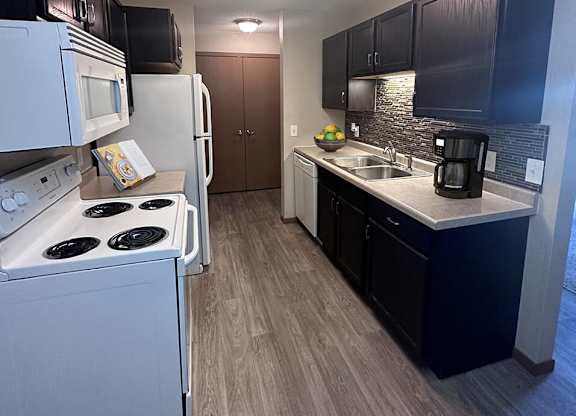 a kitchen with white appliances and black cabinets