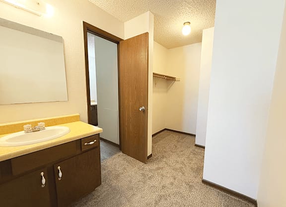 A bathroom with a sink, mirror, and carpeted floor.