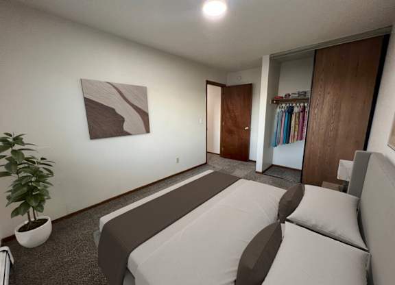A room with a bed, a plant, and a painting on the wall.