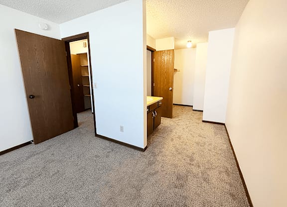 A carpeted hallway with a door on the left and a bench on the right.